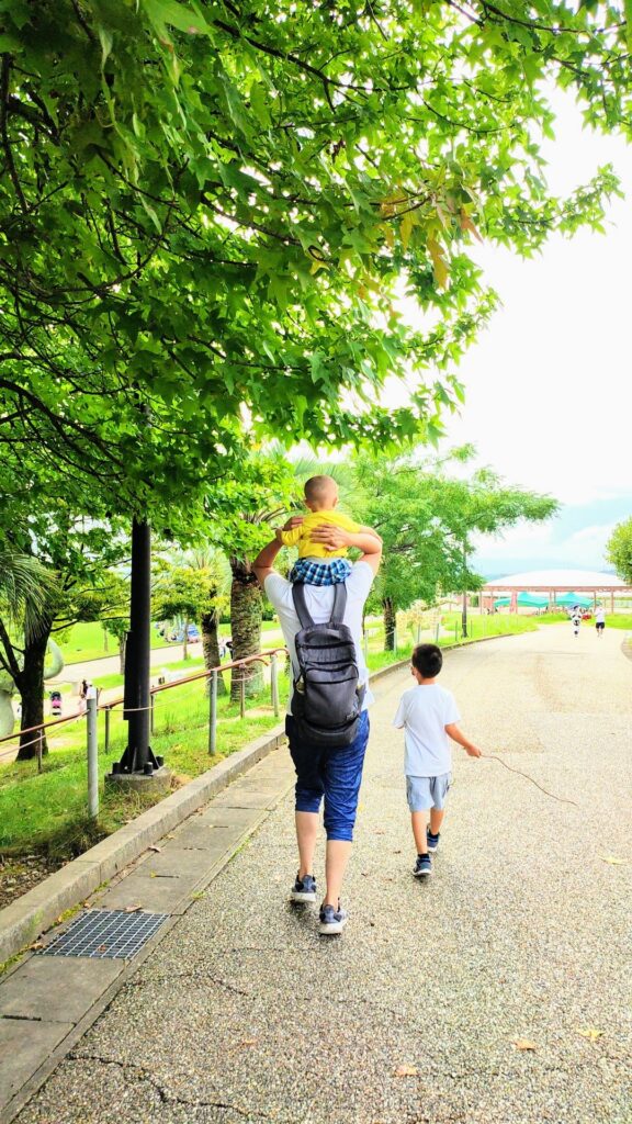 柏市の公園を歩く親子の後ろ姿。自然の中で過ごす家族の時間。（イメージ）